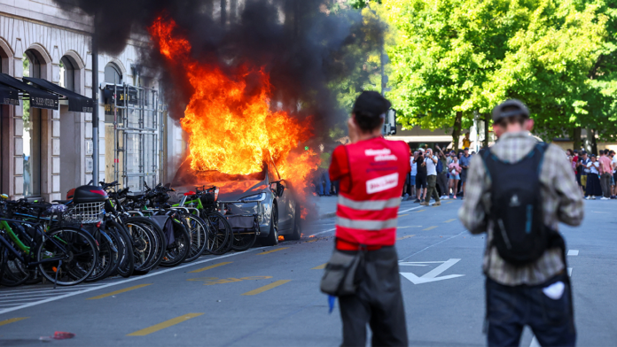 Demonstrators set fire to a Tesla, smash windows at UN office during anti-G7 protest